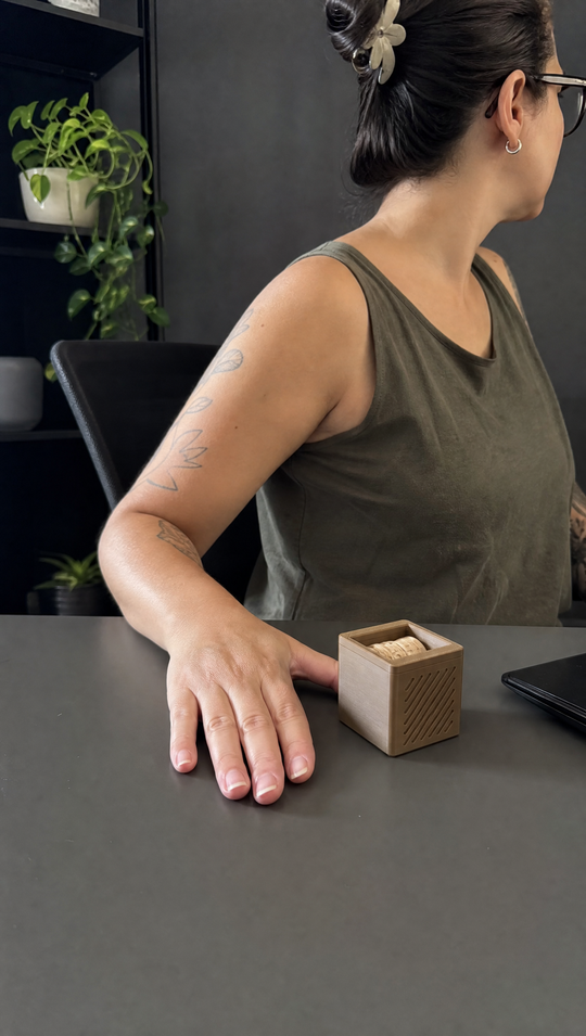 O cubo do Nigma P2 sobre a mesa de trabalho, ao lado da mão de quem trabalha