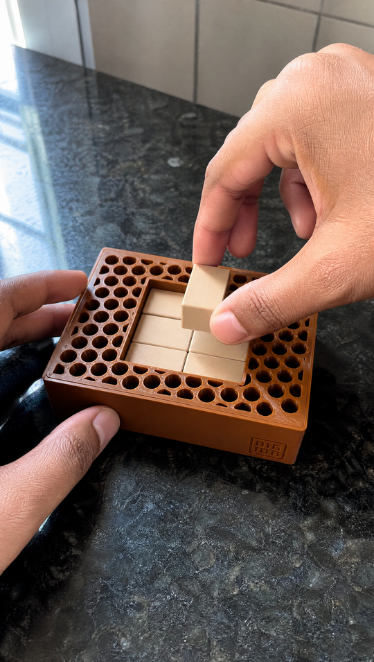 Macro das mãos encaixando um bloco creme no Nigma P3, com os furos do aro e as linhas de impressão 3D visíveis