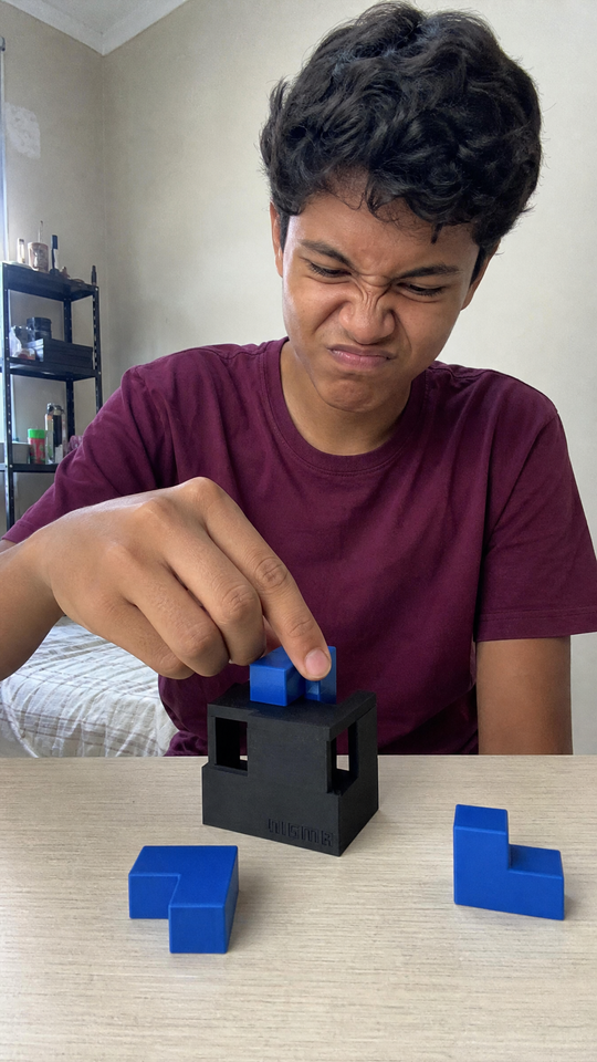 Adolescente tentando encaixar uma peça azul no Nigma P6 na escrivaninha