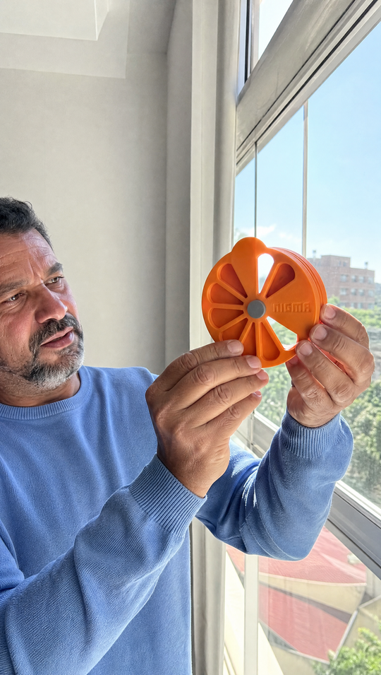 Homem estudando o Nigma P5 contra a luz da janela, com um único vão alinhado deixando a luz passar