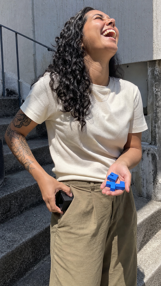 Mulher rindo guardando a caixa do Nigma P6 no bolso, com as três peças azuis na outra mão
